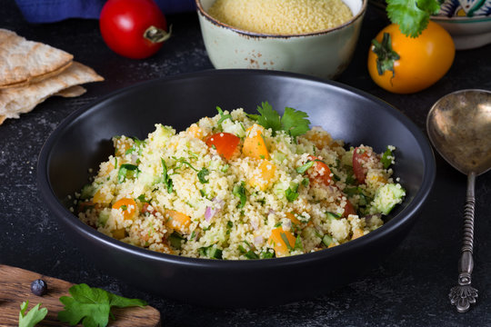 Lebanese arabic cuisine: healthy delicious salad with cous cous, fresh vegetables and greens called Tabbouleh in black bowl. Authentic cuisine