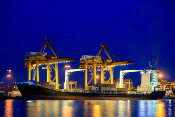 Fototapeta na wymiar Shipping port. Logistics and transportation of international import export container cargo ship with crane bridge in harbor at twilight dusk for shipping and transportation industry