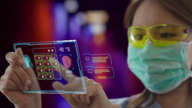 Young Asian female doctor wearing protective mask uses futuristic touchscreen holographic device to access patient's data at the hospital