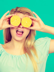 Woman holding fruit lemon half on eyes