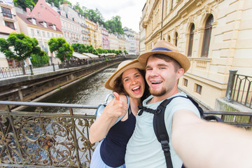 Happy young couple in love takes selfie portrait in Karlovy Vary in Czech Republic. Pretty tourists make funny photos for travel blog in Europe.