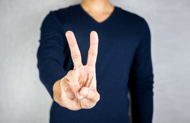 Peace hand gesture sign, two finger hand, no face man wearing long-sleeved
