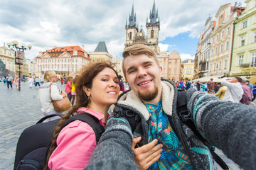 Obraz premium Happy young couple in love takes selfie portrait in Prague, Czech Republic. Pretty tourists make funny photos for travel blog in Europe.