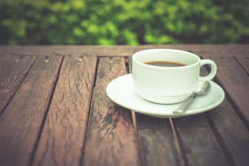 A white coffee cup on wooden table in the garden, Black coffee on wooden background, coffee break in the morning, relaxing and refreshing concepts.