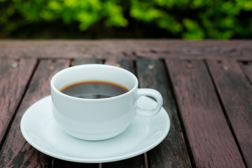 A white coffee cup on wooden table in the garden, Black coffee on wooden background, coffee break in the morning, relaxing and refreshing concepts.