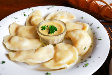 Ukrainian and Russian dish vareniki with mashed potatoes and sour cream and mushroom sauce on white plate. Close up