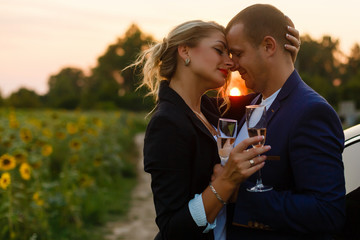 couple in the sunset, they are wearing smart casual clothes and drink champagne