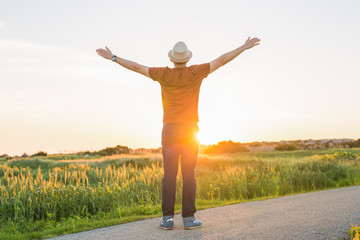 Man with arms raised, looking out over field