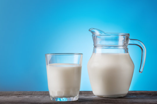 Milk in a glass and jug on a wooden table
