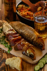 Smoked Baikal Omul on the wooden table whith a glass of beer. Rustic style, organic food.