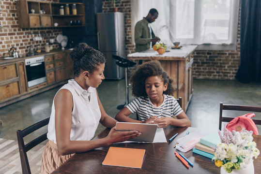 Mother showing girl digital tablet