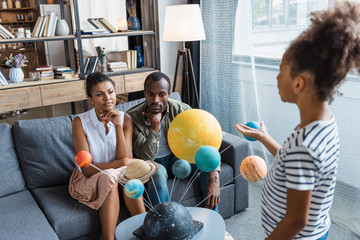 Girl telling parents about solar system © LIGHTFIELD STUDIOS