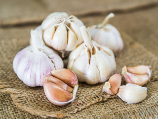 Closeup garlic clove, garlic bulb in wicker basket place on hemp sack background