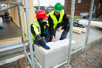 Carpenters With Plan Sitting At Construction Site