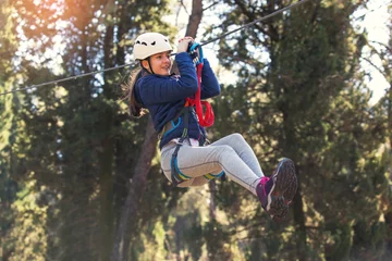 Fotobehang Happy school girl enjoying activity in a climbing adventure park on a summer day © Mediteraneo