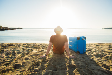 Man in sunglasses with luggage on the sea in summer sunny day
