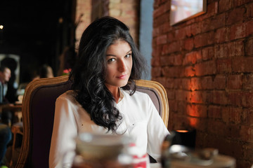 Portrait of a young woman in a cafe doing business, looking into the camera