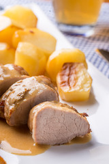 Filetto di maiale arrosto con patate e spicchi di mela arrostite servite su un piatto