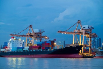 Container loading by crane, cargo ship at shipping port at twilight, Logistics and transportation concept