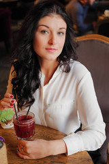 Girl drinks mulled wine in coffee shop.Lovely girl looking out the window in the restaurant and waiting for their friends. Young woman on a date in the cafe. Sexy girl in dreams is sitting in the cafe