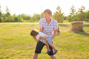 Fototapeta premium Father and son playing on the field at the day time. People having fun outdoors. Concept of friendly family