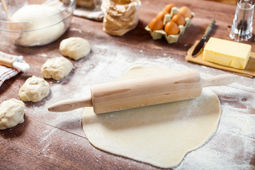 Fototapeta na wymiar Rolled out dough on wooden table with rolling pin