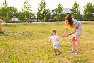 Fototapeta premium Cute cheerful child with mother play outdoors in park