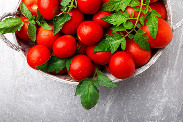 Red tomato in grey basket on grey background. Top view. Copy space. Harvest.  Full box of tomatoes.