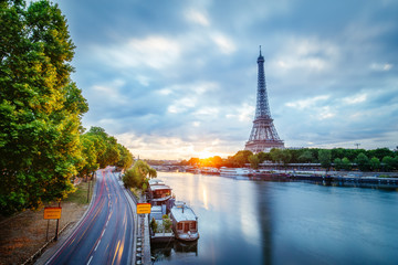 Scenic view over the Eiffel Tower from a bridge at sunrise. Paris, France. Beautiful travel background with rising sun and dramatic clouds.