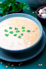Pea soup in green bowl on green wooden background. Dry yellow pea. Vegan food.
