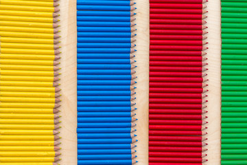 composition à partir de crayons de couleur jaunes,  rouges, verts et noirs rassemblés en bande et alignés