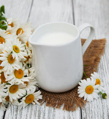 Obraz na płótnie Canvas jug with milk and chamomile flower