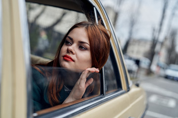 Beautiful young woman peeking out of the window of her car in the city