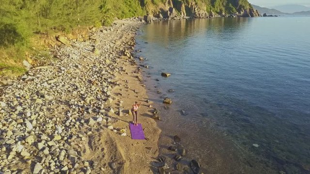 Aerial View Girl Stands in Yoga Pose on Pebble Beach