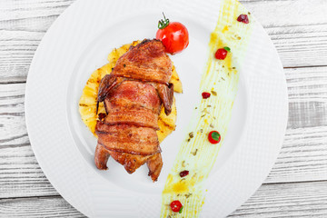 Grilled chicken in a ham with pineapple and tomatoes on plate on wooden background close up. Hot Meat Dishes. Top view