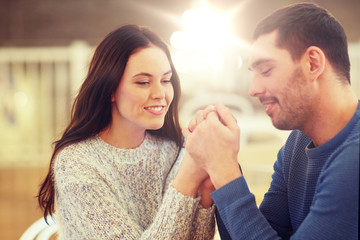 happy couple holding hands at restaurant or cafe