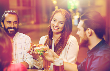 friends eating pizza with beer at restaurant