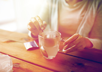 woman stirring medication in cup with spoon