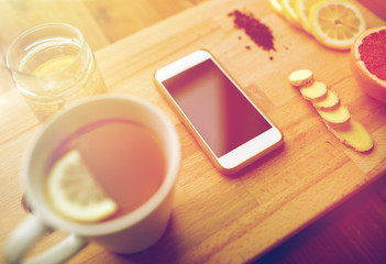 smartphone with cup of lemon tea, honey and ginger