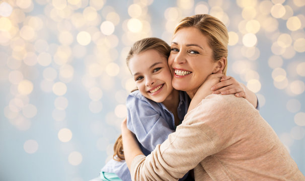 happy girl with mother hugging over lights