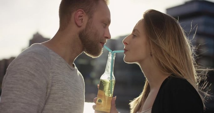 Cute young couple drinking out of one bottle with a straw