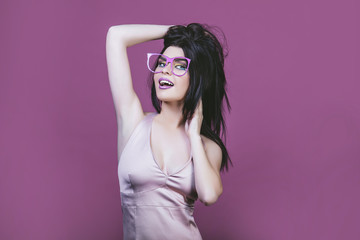 Model woman young and beautiful in the style of pop art on a pink background in pink painted glasses