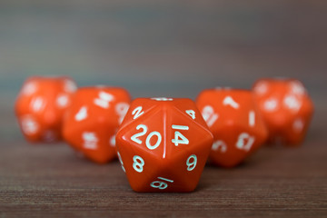 Pyramid of many red dices on wooden board. Twenty sides with white numbers. Artistic blurring....