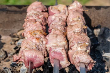 Marinated pork shashlik preparing on a barbecue grill over charcoal.