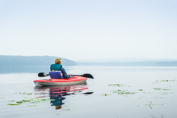 Woman enjoying a calm lake from the kayak