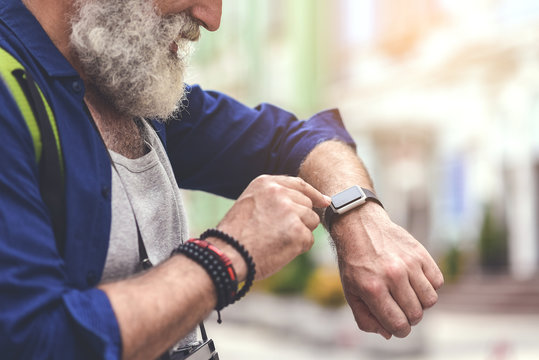 Cheerful old man touching screen of his watch