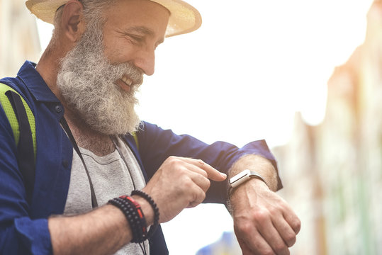 Joyful senior male tourist using smartwatch in town - Powered by Adobe