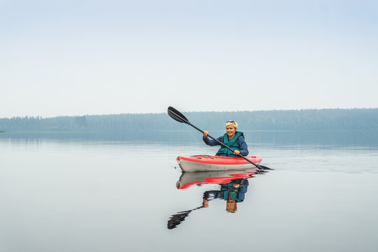 Woman Happy To Paddle From Red Kayak On Calm Lake