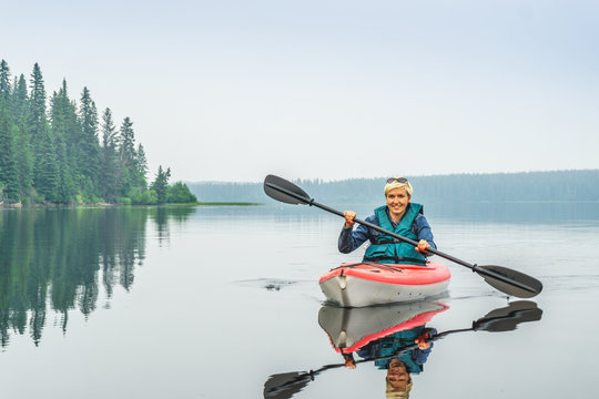 Woman Happy To Paddle From Red Kayak On Calm Lake