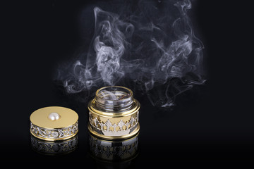Incense of Traditional Arabian Fragrance Oudh Bakhoor in a maroon glass jar on light background